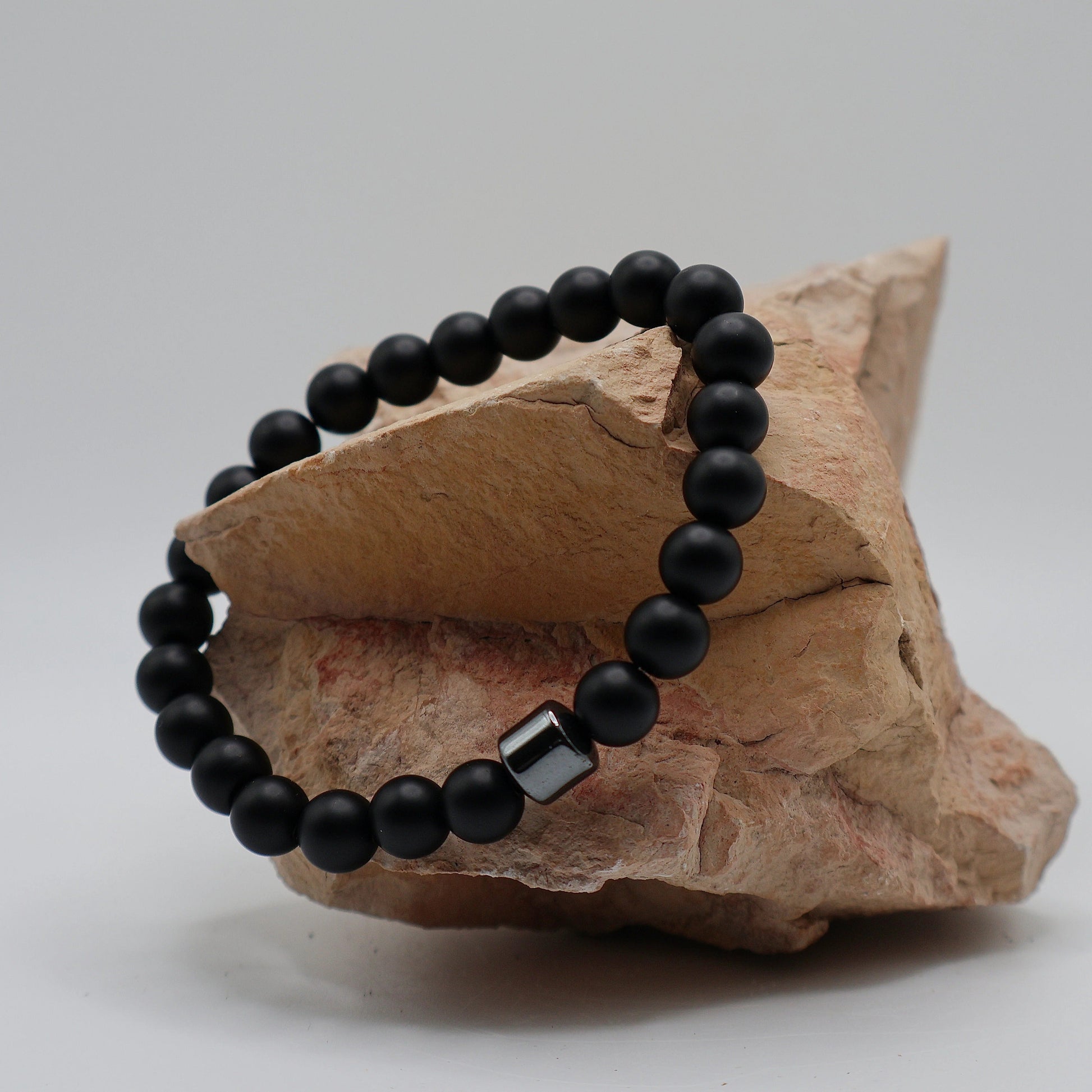 Black relaxation bracelet with a silver clasp on a piece of stone.