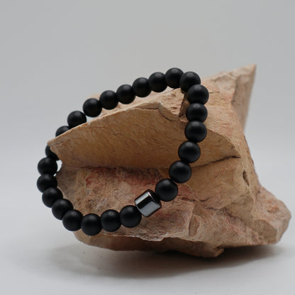 Black relaxation bracelet with a silver clasp on a piece of stone.